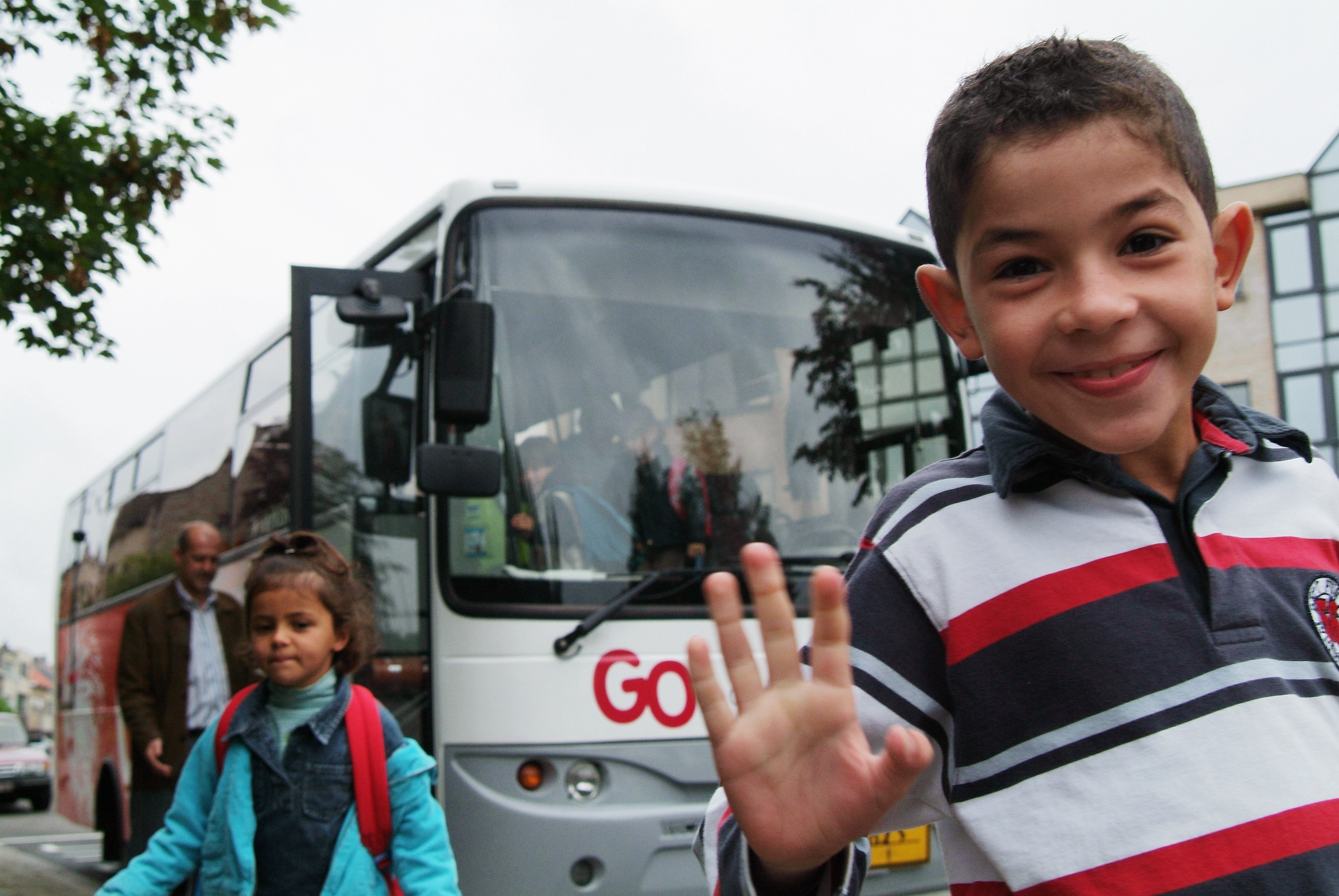 2 kinderen - op straat - zwaaien - leerlingenvervoer - sociaal - horizontaal - bus.jpg